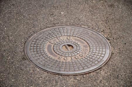 Can a manhole cover (tampa de esgoto) pose an added danger when riding a motorcycle?
